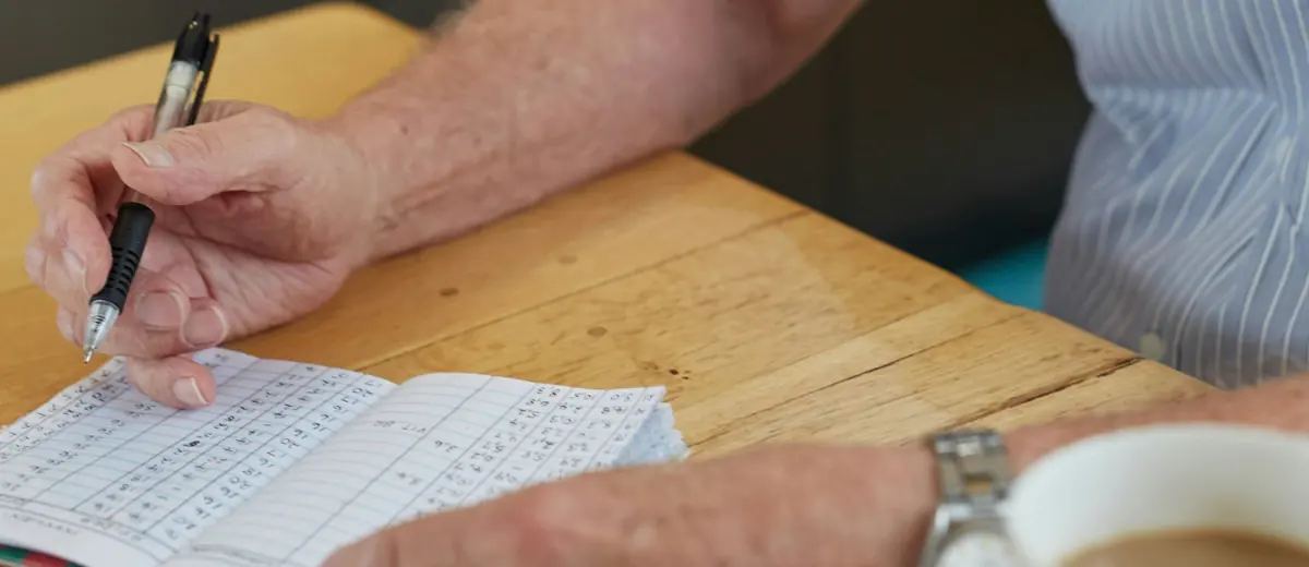 Senior si u kávy zapisuje čísla do sešitu