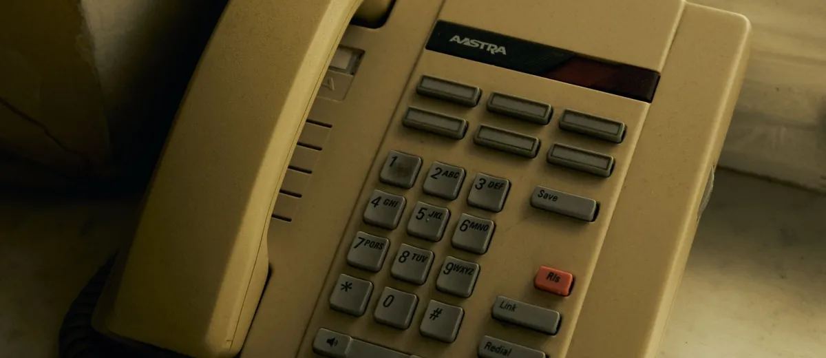 Starší pevný telefon na okenním parapetu